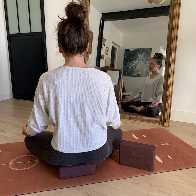 femme qui médite en étant assise sur une brique de yoga en mousse recyclée