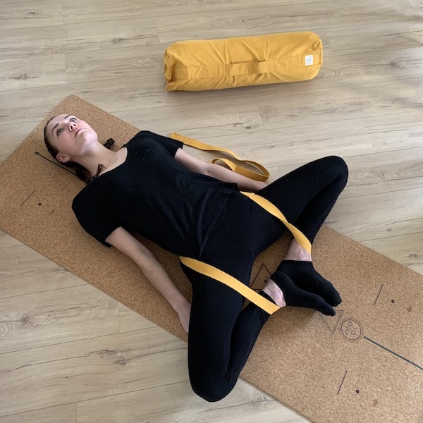 jeune femme en position du papillon allongé avec sangle de yoga yogom et tapis de yoga liège yogom