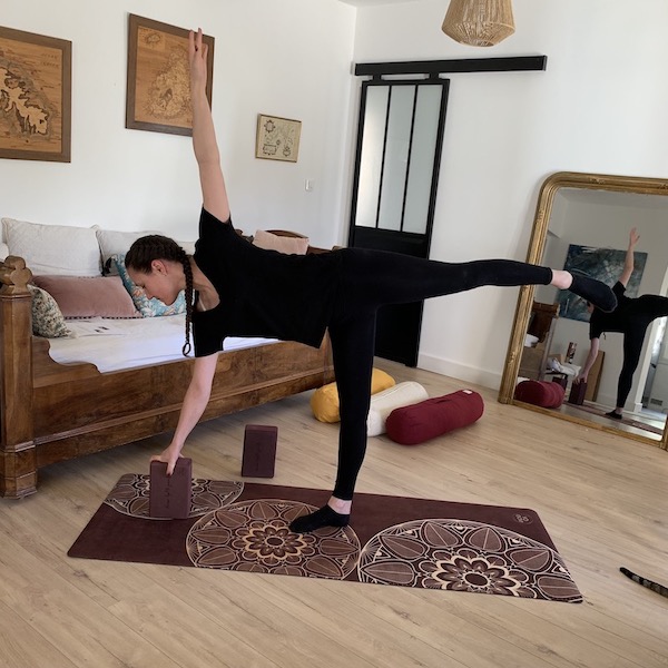 jeune femme utilise brique de yoga en mousse d'eva yogom pour réaliser posture de yoga sur tapis yogom