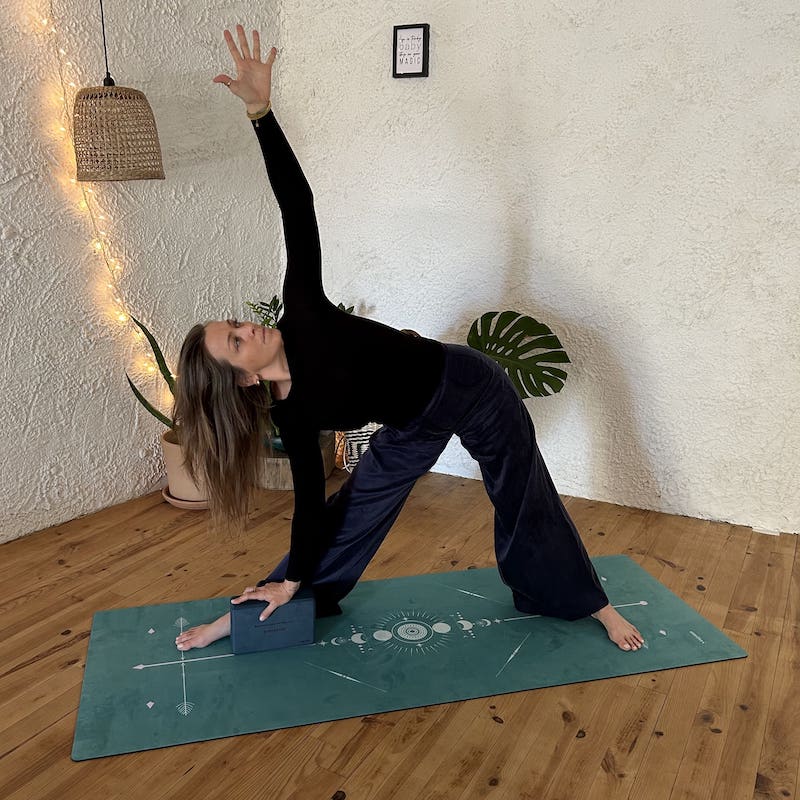 prof de yoga pratique le guerrier 2 sur tapis de yoga Yogom Performance bodyline totem vert